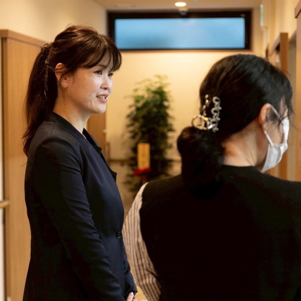 相談員が家族に施設の資料を見せながら説明する様子