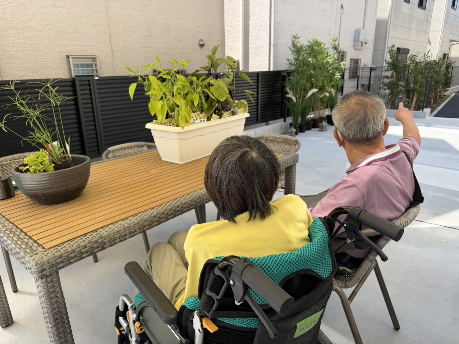 施設のテラスで入居者が植栽を眺めながら過ごしている様子