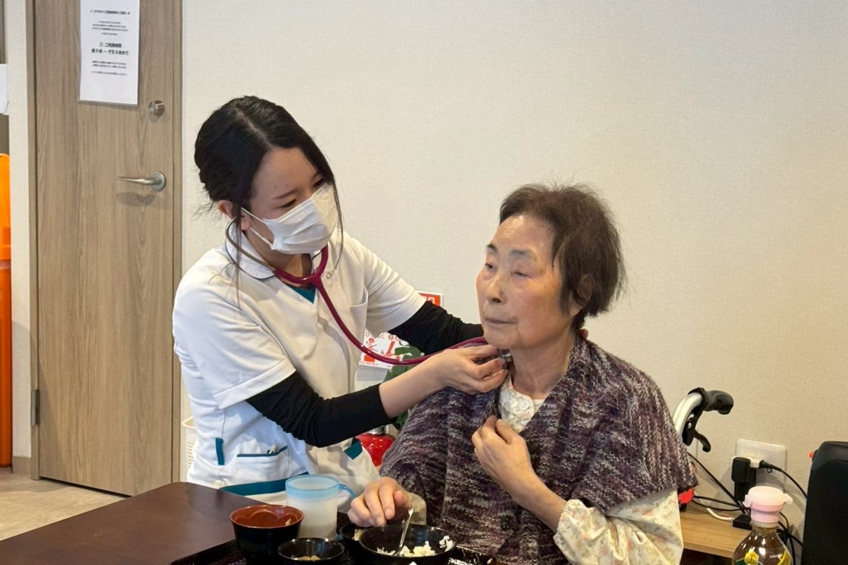 看護師が入居者の状態を聴診器で確認している様子
